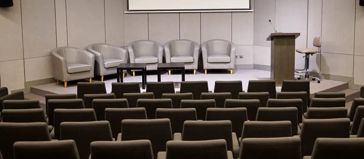 Konferenciaterem napközben: széksorok, pódium és kivetítő